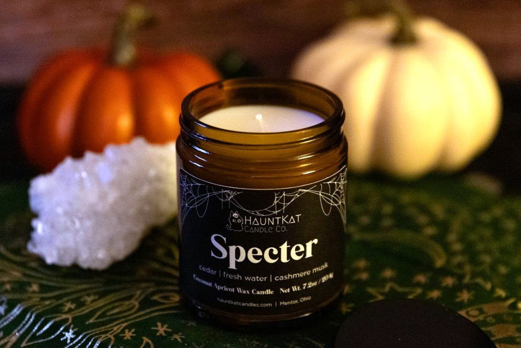 Specter candle in a glass jar with pumpkins in the background