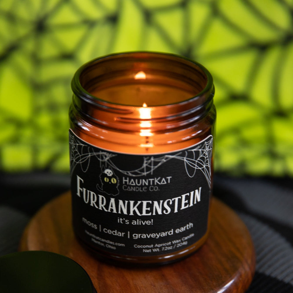 Candle in a glass jar with a label on a wooden coaster against a green spiderweb background